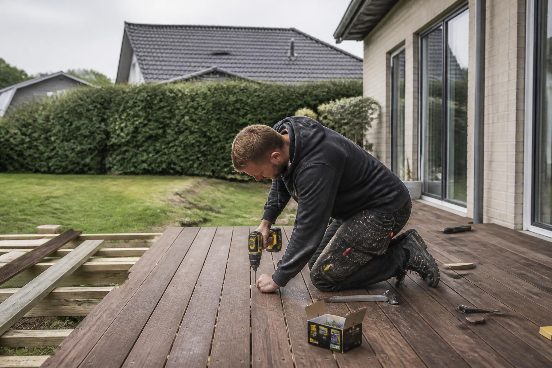 Tømrer lægger nye terrassebrædder ved en dansk villa