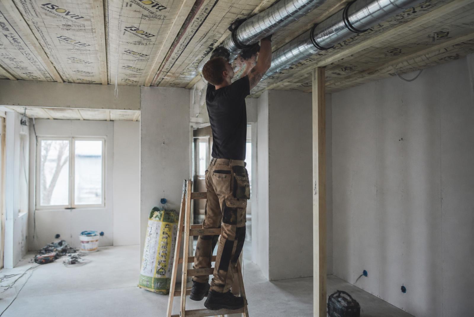 Montør installerer ventilationskanaler under loftet i en dansk bygning